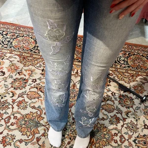 Lågmidjade jeans  - Säljer dessa lågmidjade jeans med blommor på benen och pärlor, de är i strl M men skulle säga att de passar S med💕 superfint skick förutom knappen som är lite lös och glappig