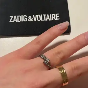 Säljer denna ring då den inte kommer till användning. Säljs tyvärr inte längre hos Zadig & Voltaire. Den har tappat två nitar. Den har även rostat lite vid sidorna.