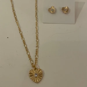 Guld halsband men hjärta+guld örhängen med hjärta - Ett jätte gulligt guld halsband med ett hjärta med en liten Sten i+örhängen också men hjärta med Sten i. Båda för 50 kr 