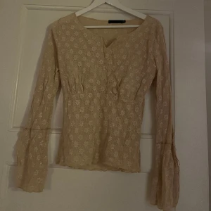 Stickad blus  - Supersöt stickad blus med blommor och glitter samt vida ärmar med snörning. 