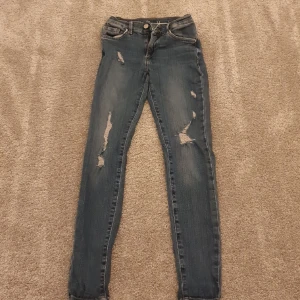 Stretchjeans från Never Denim i strl XS - Blå jeans i stretch och skinnymodell. Använda men i gott skick 