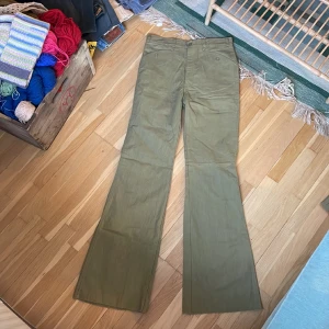 Vintage 90-tals byxor Dobber  - Vintage utsvängda byxor från Dobber, grönbeige färg. Helt nya med lapp kvar, endast legat på lager.  Obs det är rålängd, de är alltså inte fållade utan bör sys upp i ens egen längd. Märkta size 32, inseam 36.  Mått cm: Midja: 38 Höft: 46,5 Ben: 87  