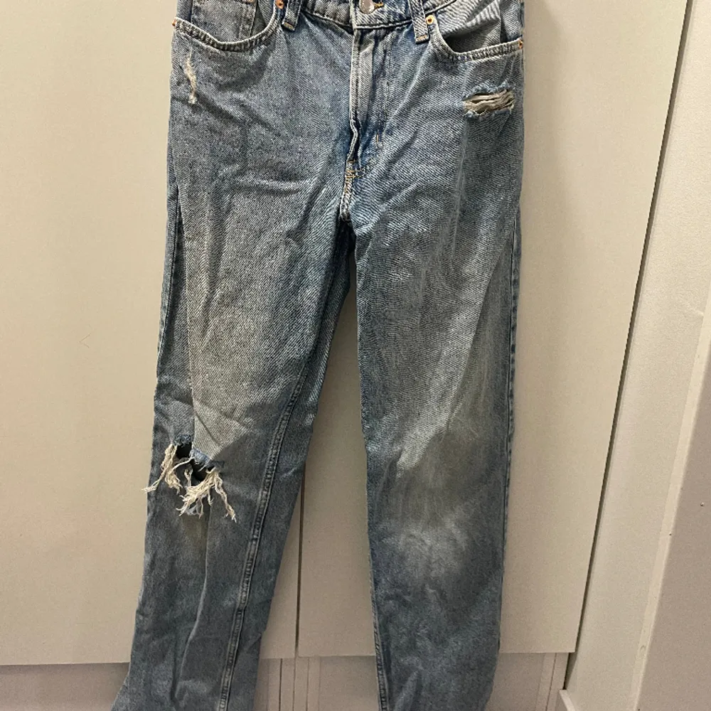 Blåa low waist bagy jeans från H&m med hål på ena knäet. Storlek 34. Jeans & Byxor.