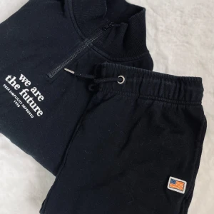 Mjukisset - Säljer ett svart mjukisset ifrån Svea. En svart halfzip med vitt tryck på bröstet och ett par svarta mjukisbyxor med snörning i midjan och mudd nertill. Använt fåtal gånger så fint skick! 