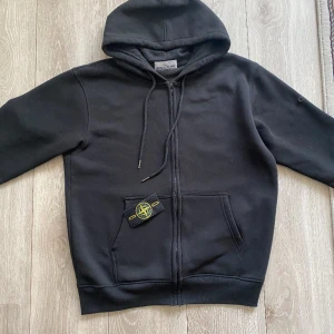 Stone island zip hoodie  - Säljer nu min stone island hoodie eftersom den inte kommer till användning. Skick 10/10 inga defekter den är som ny. Tröjan är självklart äkta har tyvärr inget kvitto men det är bara att scana Qr koden. Priset kan diskuteras vid snabb affär.