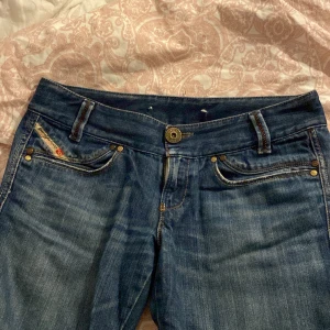 Diesel jeans lågmidjade - Jätte snygga äkta diesel byxor som är lågmidjade! De är även lite utsvängda där nere vid fötterna. Har lite skador nere men dom är inte synliga när dom är på. Det finns andra hål inuti som jag satt fast med snöre. Priset kan diskuteras 