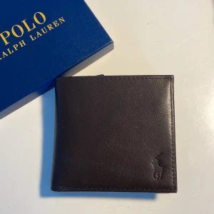 Ralph lauren plånbok - Tjo! Säljer min helt nya ralph lauren plånbok i äkta läder! Tags, låda och kvittot ingår! Nypris 1049kr, mitt pris 400kr. Priset är inte hugget i sten! Kom vid minsta lilla fundering! 🍾🍾