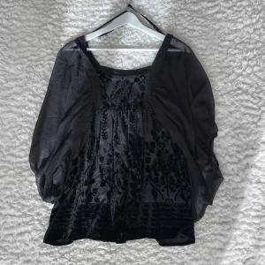 Svart blus med detaljer - Jättesnygg och trendig svart blus. Detaljer, också i svart, men i annat material. Jätteluftig. Köpt för väldigt länge sedan för 350 kr, men aldrig använd.