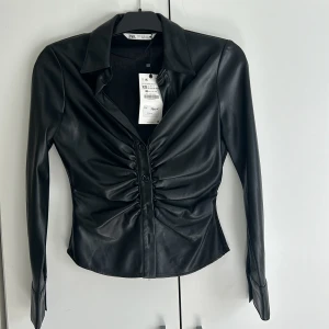 Skjorta i skinnimitation från ZARA - Skinnskjorta i XS köpt från Zara för 399kr och säljer för 200kr. 