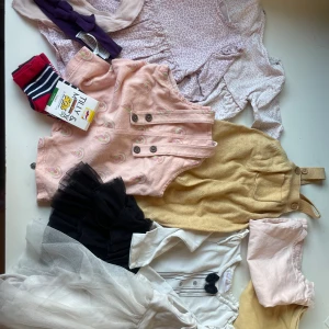 Klädpaket flicka -  2 t-shirts (en body) 2 hängselbyxor (en kort & en tunnare virkad) 4 klänningar varav en är som en body Strumpor, en dregglis och hårband.   Skicket är blandat, obehandlade fläckar KAN finnas men generellt sett fint skick