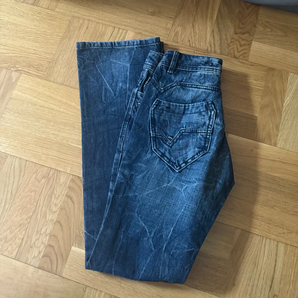 Mörkblå/gråa jeans i spräcklig färg. Flare. Mått: midja rakt över 35cm. Innerbenslängd 78 cm. w26 l32. Jeans & Byxor.