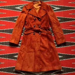 70- 80-tal, Mocka Kappa - Underbar, hangord kappa i tegelröd mocka (lite kallare än på bilderna) med fantastiska detaljer från sent 70-tal till tidigt 80-tal! Den har använts men är i mycket fint skick. Längd-118cm Axlar-38cm Bröst-44cm Midja-38cm Ärm-56cm Skärp-135cm! 🩵