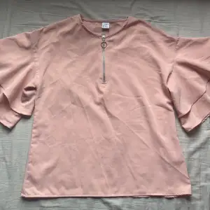 En rosa blus med volangärm och dragkedja fram från Lindex. Den är i storlek 152 men den passar även om man har storlek XS. Orginalpris 199 kr