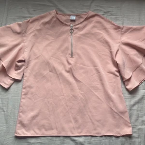 Blus med volangärm  - En rosa blus med volangärm och dragkedja fram från Lindex. Den är i storlek 152 men den passar även om man har storlek XS. Orginalpris 199 kr