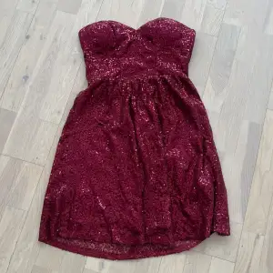 En kortare vinröd klänning med paljetter