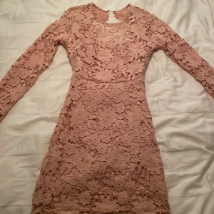 Rosa spetsklänning - Rosa spetsklänning med öppen rygg och sidenband samt dragkedja i mycket bra skick, endast använd en gång
