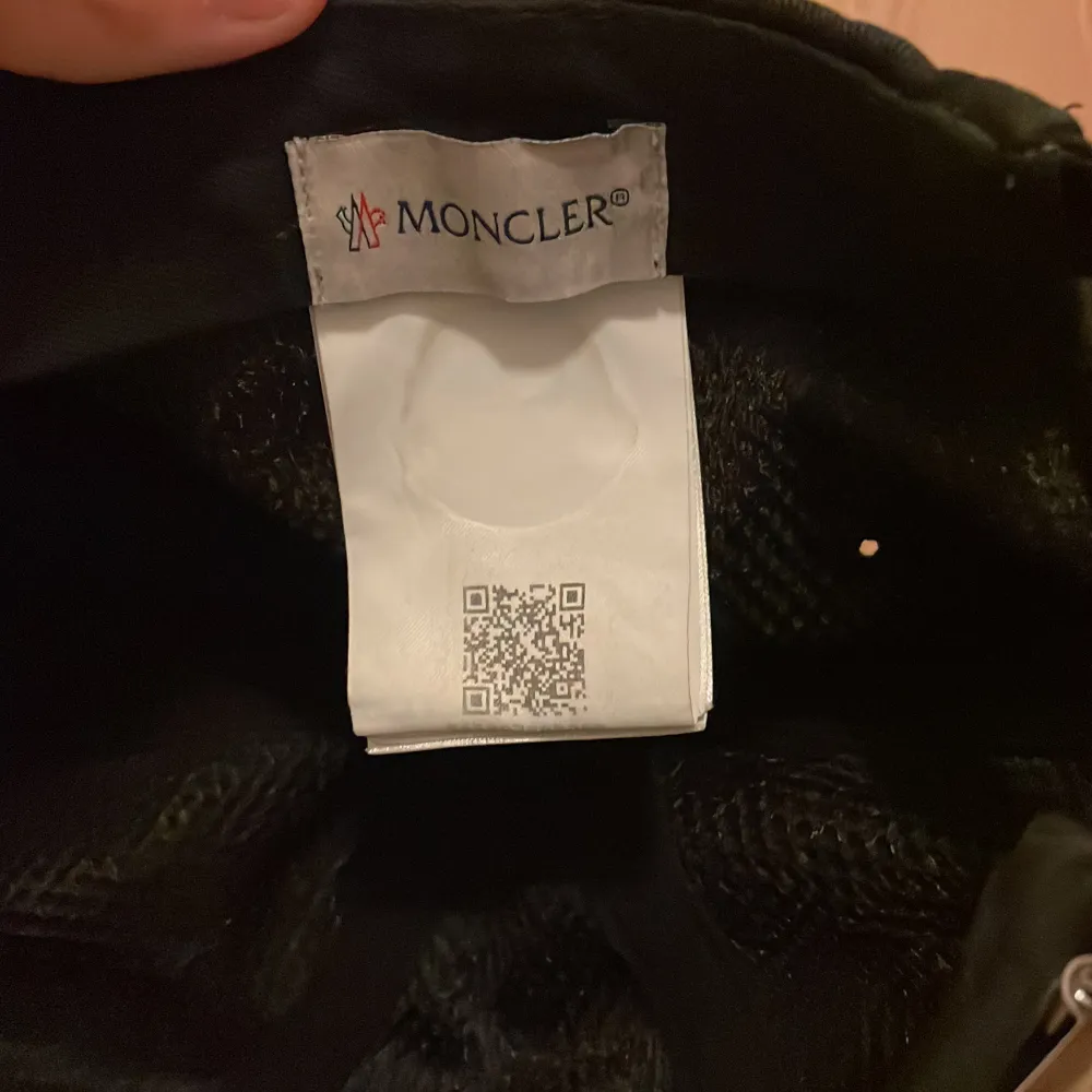 En moncler keps som är köpt för ett par år sedan, den är i bra skick eftersom att jag har färgat den för den var solbränd ( qr kod och allt funkar fortfarande) Det tråkiga var att när jag färgade den så fick spännet bak fick lite färg. (Bud pm) . Accessoarer.