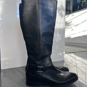 stövlar - tommy hilfiger  - Svarta stövlar i äkta skinn, dragkedja på insidan. Orginalpris 2000kr. Knappt använda.  Höjd 44cm  Omkrets vad 39cm  Klack 2cm