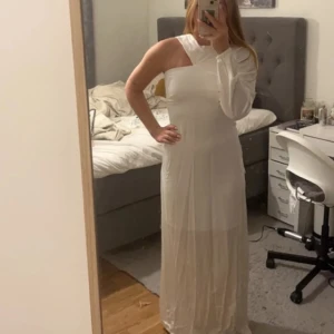 Vit långklänning med en arm - En fin vit långklänning med en arm, helt oanvänd lappen finns kvar, aldrig fått tillfälle att använda den därför är den oanvänd