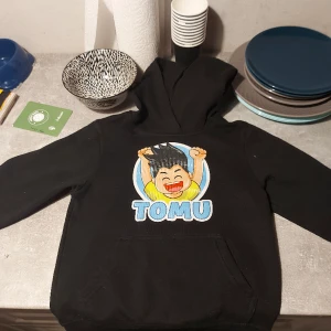 Tomuhoodie - Hoodie med Tomu storlek 110/120. Fint men använt skick. katt finns i hemmet.