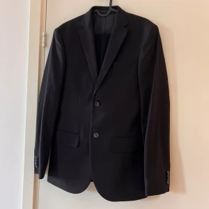 Kostym svart - Kavaj strl 44 Slim fit Byxa strl 31 Slim fit   Nyskick, endast använd en gång.