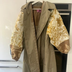 Trenchcoat - Superhärlig trenchcoat med påsydda oversized ”puffärmar” i olika motiv. Köpt i Milano tidigare i år och har dessvärre inte kommit till användning.  