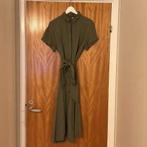 Klänning - Fin figursydd klänning med knappar och knytning. 