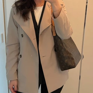 Kort trenchcoat  - Kort beige trenchcoat med snören! Superfint skick. Säljer då den inte kommer till användning längre! Storlek XS🌷