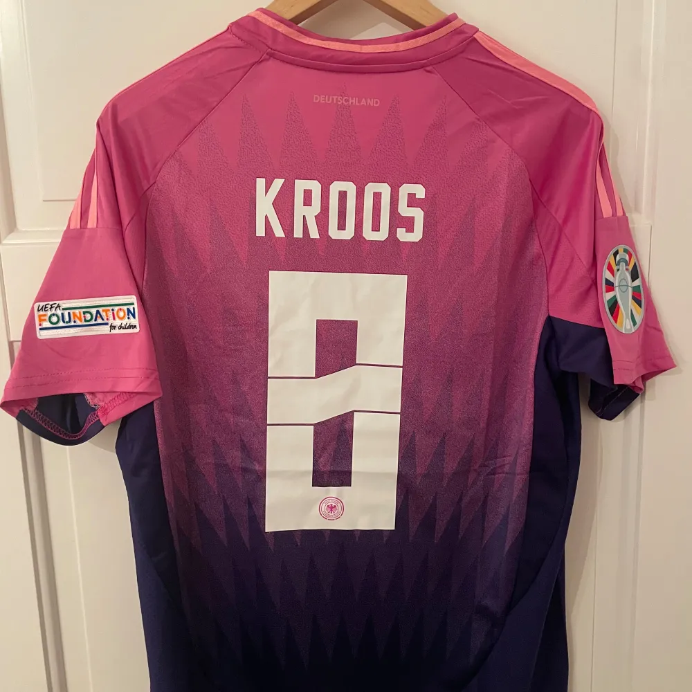 Säljer Tysklands bortatröja från sommarens EM med Kroos #8 printat på ryggen. Helt ny med tagg. Tröjan är en reprint. Storlek: M. Ansvarar ej för postens slarv. Endast handtvätt. Gnugga ej på blöta prints.. Sportswear.