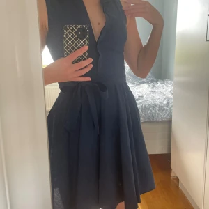 Marinblå klänning  - Marinblå skjortklänning med kort ärm från Amisu i stl 34. Har avtagbart skärp i midjan, dragkedja på sidan och uppknäppbara knappar framtill. Använd mycket få gånger.