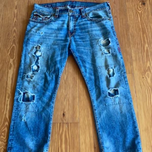 True Religon Jeans - Ricky modellen med mycket rips. W36 så dom sitter fint oversize! Lite korta dock uppskattar de som L30. Mått kan fås i DM! Skick 6/10 därav pris, fattas en knapp där bak och stygn gått upp vid foten.