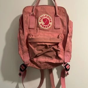 Fjällräven skånken, mini - Kånken miniryggsäck, i rosa, ganska använd och saknar tyvärr sittunderlaget som brukar ingå i den.  Man ser att den är använd (går med all säkerhet att tvätta) utöver det är den i bra skick.