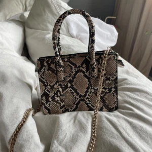 HM väska - Säljer denna helt oanvända väskan från HM. Guldiga detaljer och avtagbar längre kedja.😊