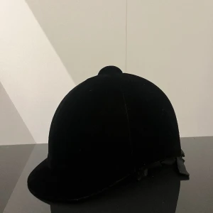 Ridhjälm  - Ridhjälm i toppenskick Rosett på baksidan Sammet