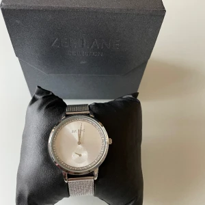 Silverfärgad klocka med vita stenar -  •Fin klocka i bra skick med justerbart klock armband •Batteri behövs •Använd 2 gånger •Märke: Zee Lane •Originalbox medföljer 🚫Djurfritt och rökfritt hem 📍Kan mötes upp i Mölnlycke centrum