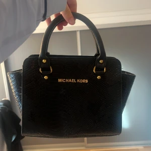 söt mk väska - säljer min söta michael kors väska, svart med guldiga detaljer, och lite ”orm” mönster! priset kan diskuteras!