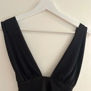 Oanvänd svart festtopp - Svart oanvänd festtopp i strl XS. Knytning som man kan knyta antingen runt nacken eller över axlarna. Lappar sitter på. 