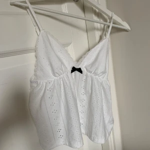 Vit topp - Säljer detta supersöta linnet då den var lite stor för mig 🤍 endast använd 2 ggr men har tyvärr fått en liten sminkfläck på ena bandet som man ser på sista bilden men det borde gå bort i tvätten 🤩 nypris = 80kr 