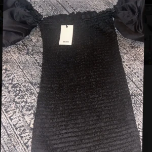 Svart klänning  - Ej använt klänning från Bik Bok! . Klänningen passar till dig med storleken S eller XS utan några problem. Puffiga korta armar ger en elegant touch som gömd i klänningens design.