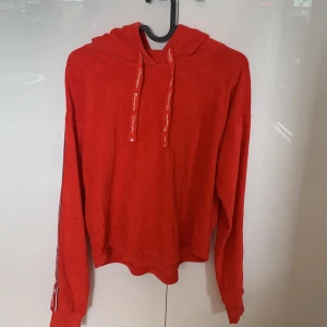 Champion Röd Handduksmaterial - Köpte denna tröja för inte så länge sedan, men jag växte ur den snabbt så den hann inte komma till så mycket användning, så skicket är väldigt fint! Tröjan är en riktigt skön tröja att bära!