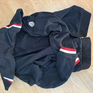 Moncler zip hoodie  - Storlek M Sitter bra och skit fint skick Osäker om denna äkta då dragkedjan är ej samma som min äkta jacka men den funkar såklart och annars ser den extremt bra ut