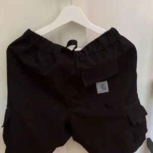 Carhartt shorts XS - Snygga shorts i cargomodell men mer av snyggbyxe-feeling. Använda men felfria och lika svarta som vid nyköp. Nypris 849 kr.