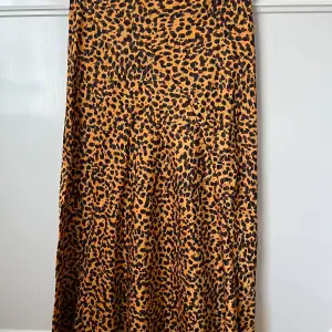 Vadlång kjol i sidenlikt tyg, leopardmönstrad. Dragkedja i sidan. 