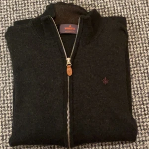 Stickad Morris helzip - Stickad i merino ull. Väldigt bra skick. Väldigt härlig mörkgrön färg som passar snyggt till allt. Har krympt lite eftersom det är merino ull, men skicket är fortfarande super. Passar storlek S. Nypris är 1899.