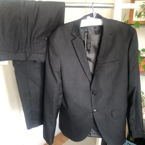 Kostym - Kostymen är köpt och använd av en ung kille. Den är endast använd ett par gånger, kavajen är i strl 50, kostymbyxorna i strl 54, märket Jack & Jones.