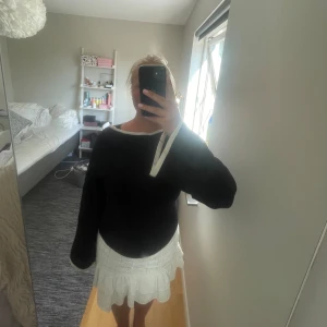 Svart finstickad tröja  - Svart tröja som är väldigt tunt stickad. Tröjan är finstickad men materialet är väldigt tjockt och tungt vilket gör att den känns lyxig! Den har en vit rand kring halsen och ute på armarna. Storlek L men är liten i storleken. 