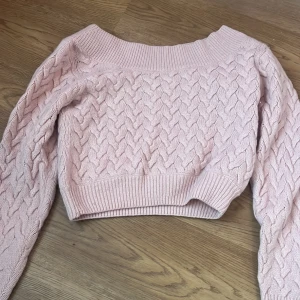 Rosa stickad tröja från & Other Stories - En rosa stickad tröja från & Other Stories med ett flätmönster. Tröjan har långa ärmar och en ribbad kant vid ärmslut och nederkant. som är off sholder om väldigt fin och mysig till hösten