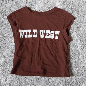 Brun t-shirt från H&M Divided - En brun baby tee från H&M med tryck i vitt på framsidan. 