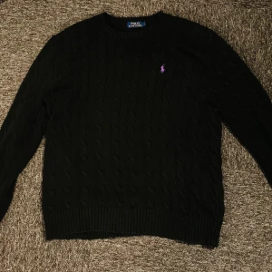 Ralph Lauren CableKnit Sweater Lila logga - Riktigt skön Ralph Lauren tröja med lila logga. Köpt för 2200kr av min vän. Tröjan är 100% äkta, gjord av 100% ull och är av väldigt bra kvalite. Tröjan är i storlek L men sitter mer mot M. Inga slitningar eller fel. Skriv vid funderingar👍🏼