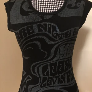 cool retro topp m. tryck framtill - ascool svart topp med blåskimrande tryck från 90-talets gina tricot !! väl använd men utan några defekter förutom att färgen är en aning urtvättad från den neonblåa färgen den hade från början men fortfarande lika snygg <3 passar xs-s